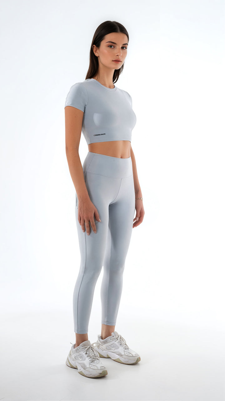 Açık gri kadın crop top ve yüksek bel tayt giyen model uzak ön çapraz görünüm