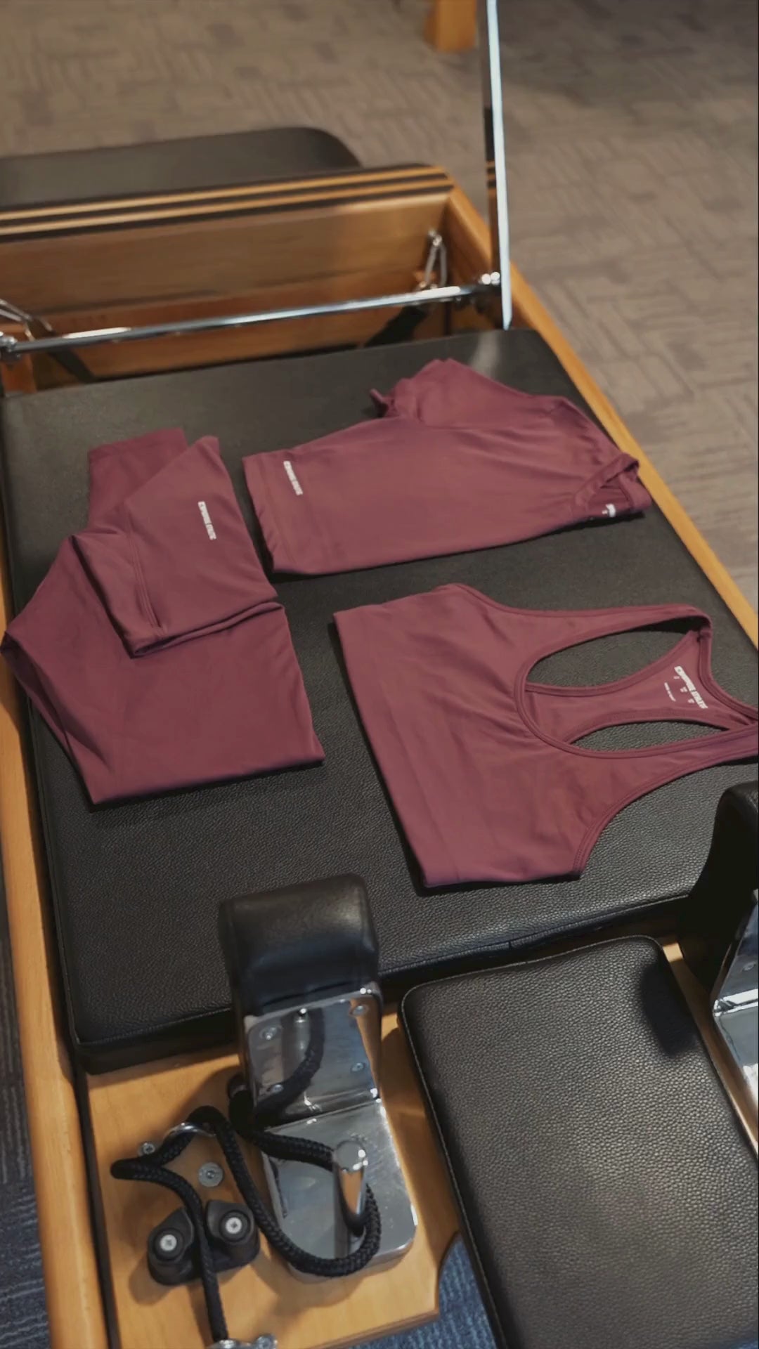 Bordo kadın spor tişörtleri – Pilates reformer üzerinde şık ve fonksiyonel antrenman kıyafetleri.